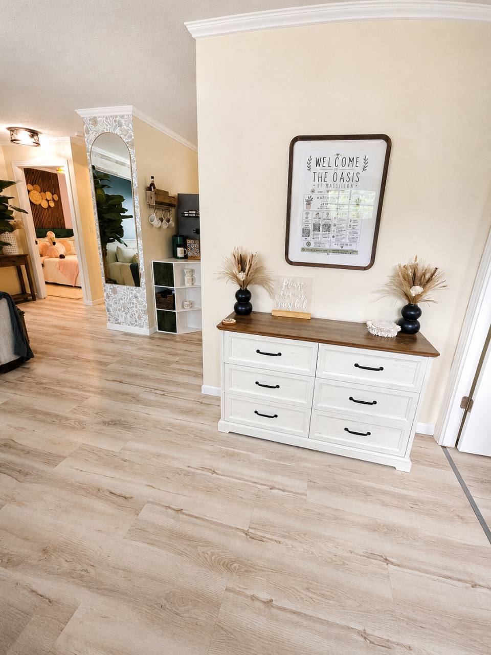 Entry area with a white dresser and framed welcome sign for The Oasis of Massillon
