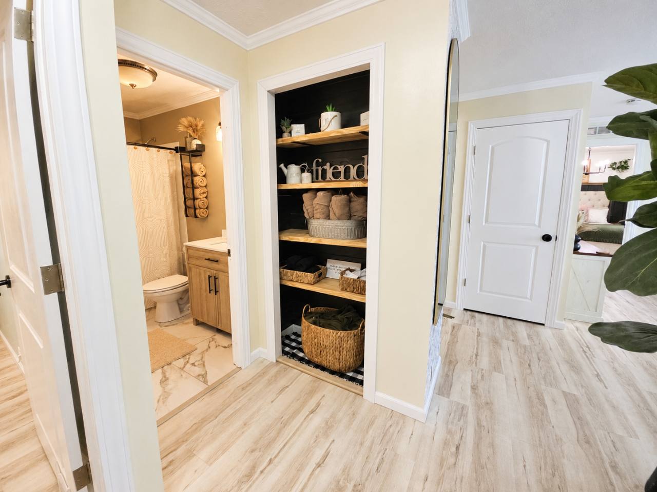 Hallway with open shelves, baskets and a view into the bathroom