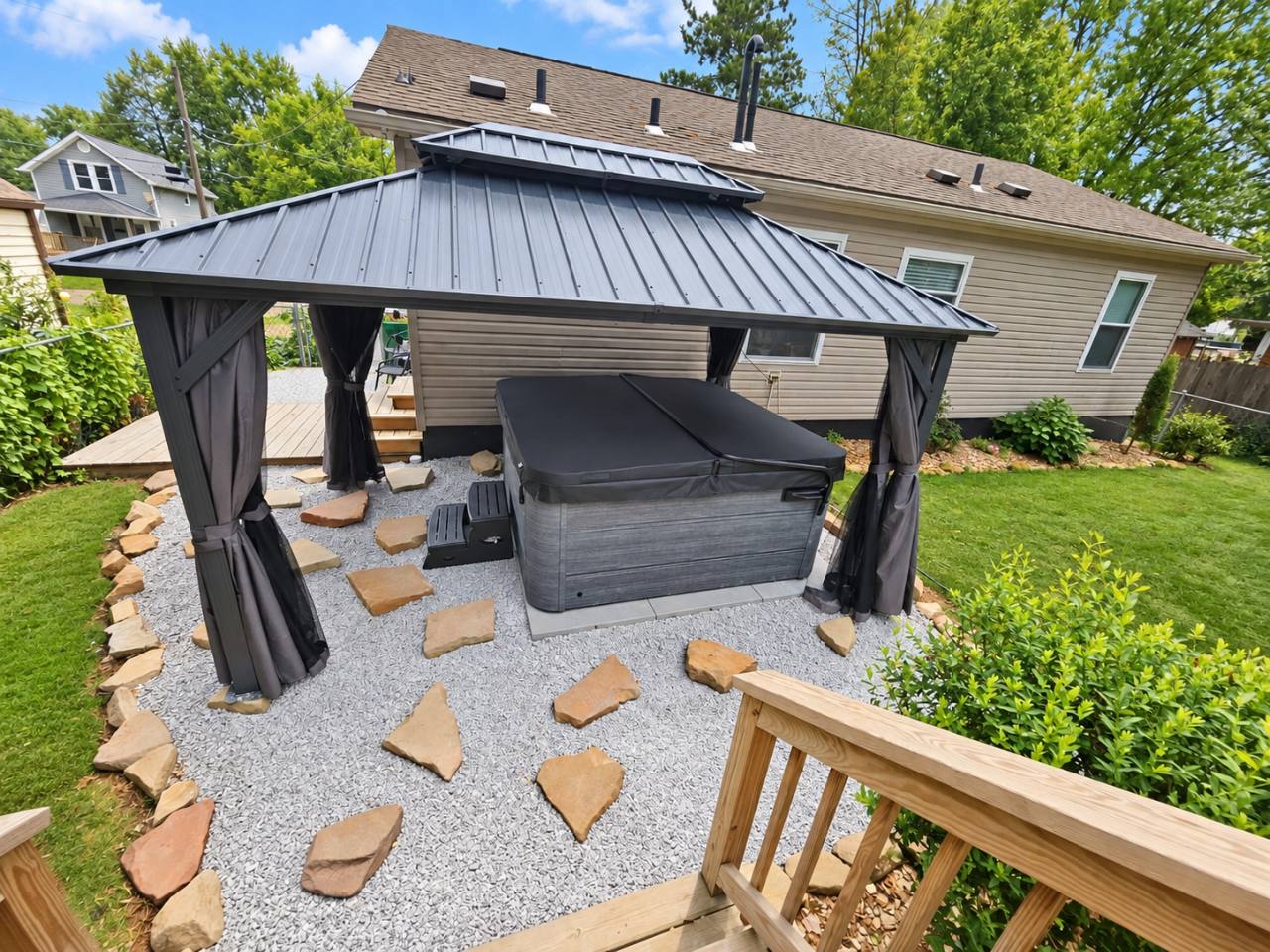 Covered hot tub beneath the gazebo, with stepping stones and the backyard viewed from the deck