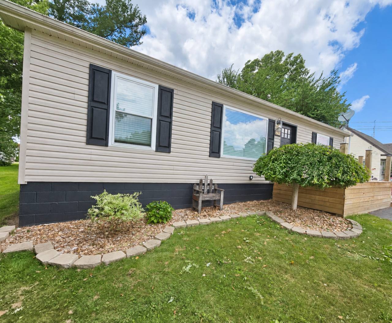 The Oasis of Massillon house exterior with beige siding, black shutters, lawn and landscaped front porch