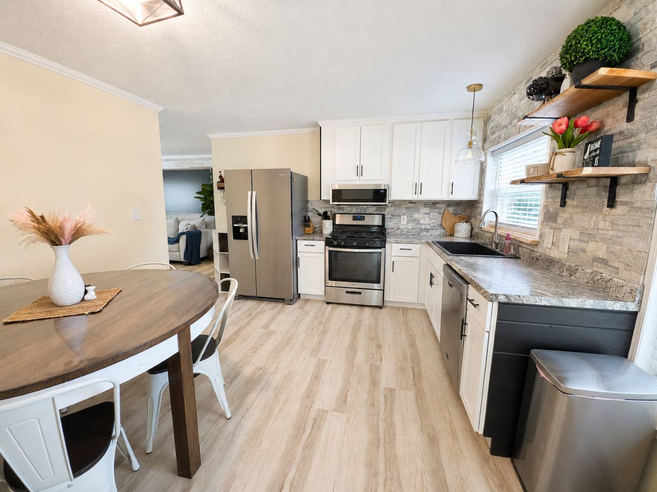 Kitchen with white cabinets, stainless steel refrigerator, gas range, microwave, dishwasher and wooden dining table