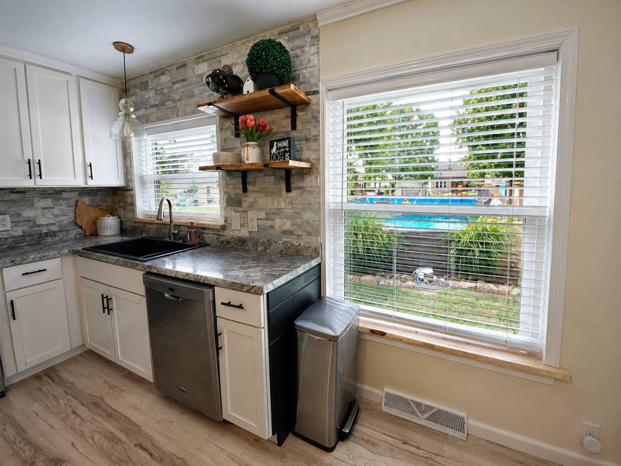 Kitchen countertop, sink and dishwasher with windows overlooking the backyard pool