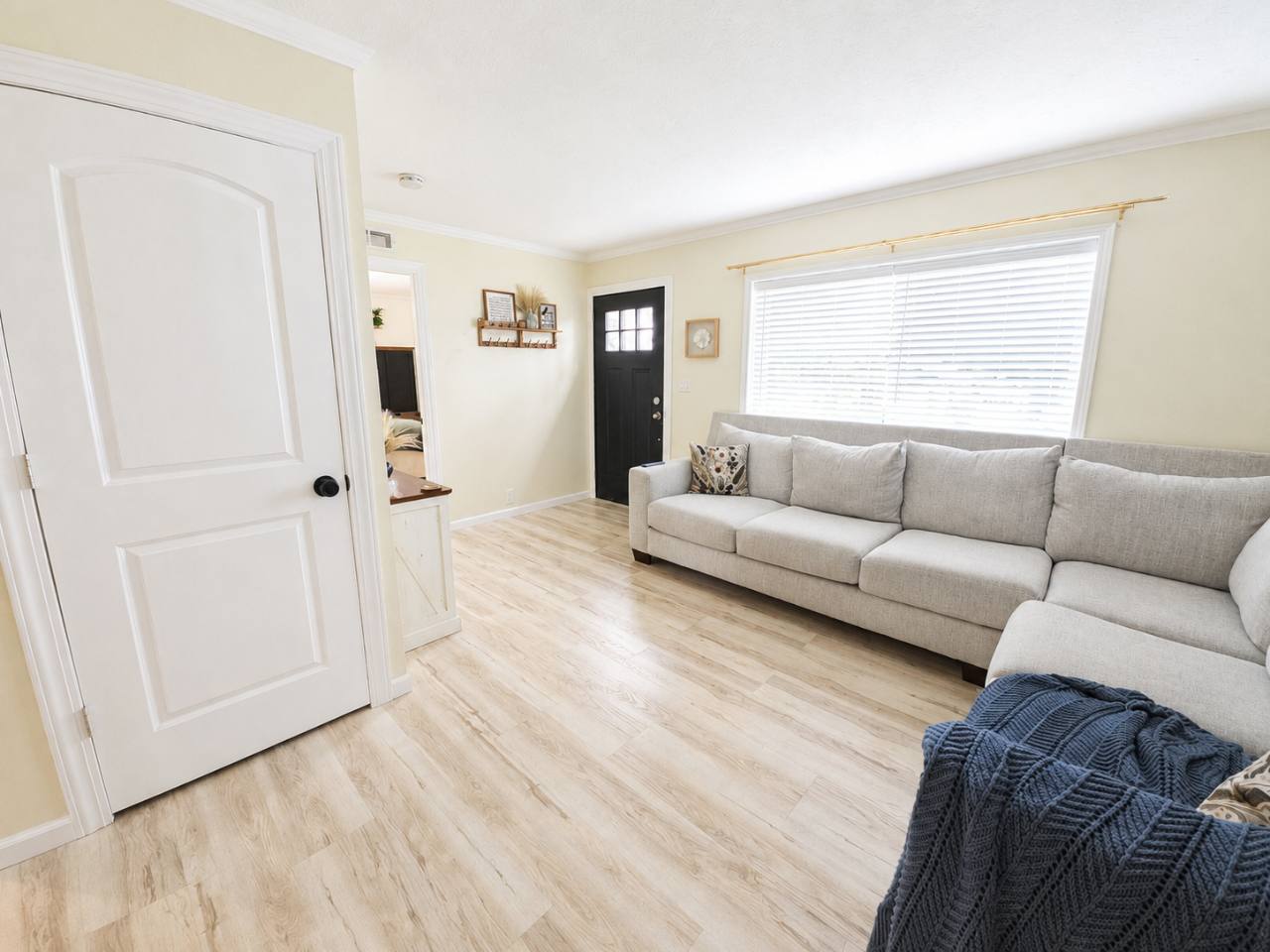 Bright living room with a gray sectional sofa, large window and front entry door