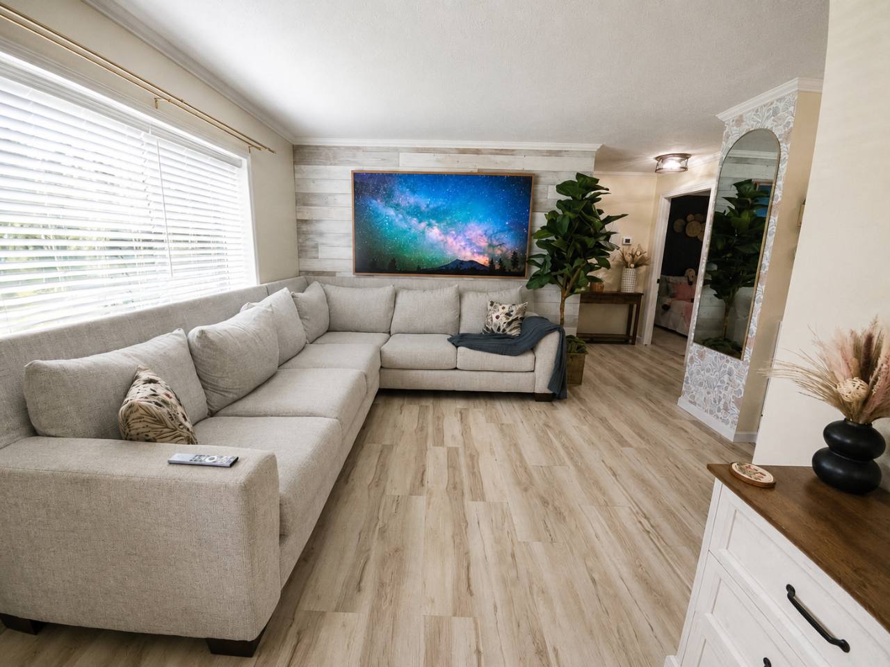 Living room with a gray sectional sofa, large wall-mounted television and a tall mirror