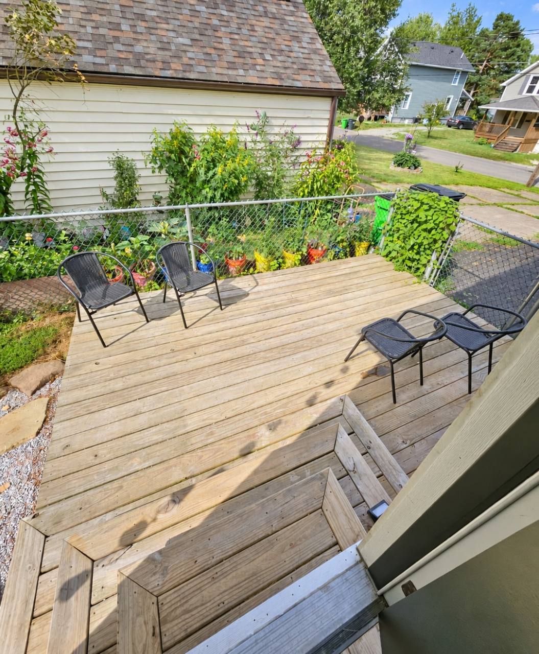 Wooden deck with outdoor chairs, steps and an adjacent fenced area at The Oasis of Massillon