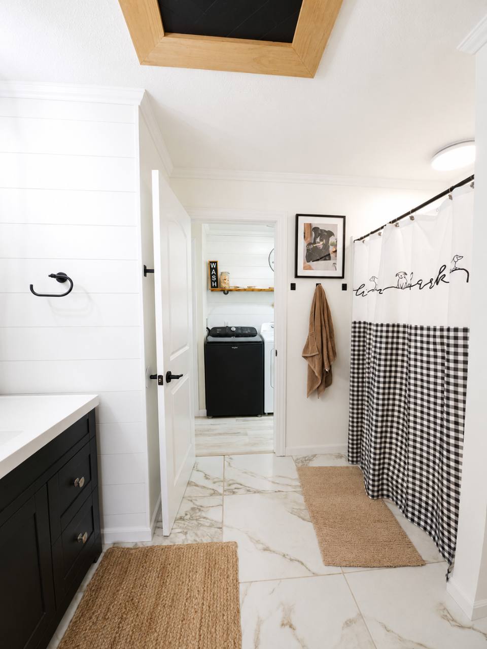 Second bathroom with black vanity and checked shower curtain, looking into the laundry room