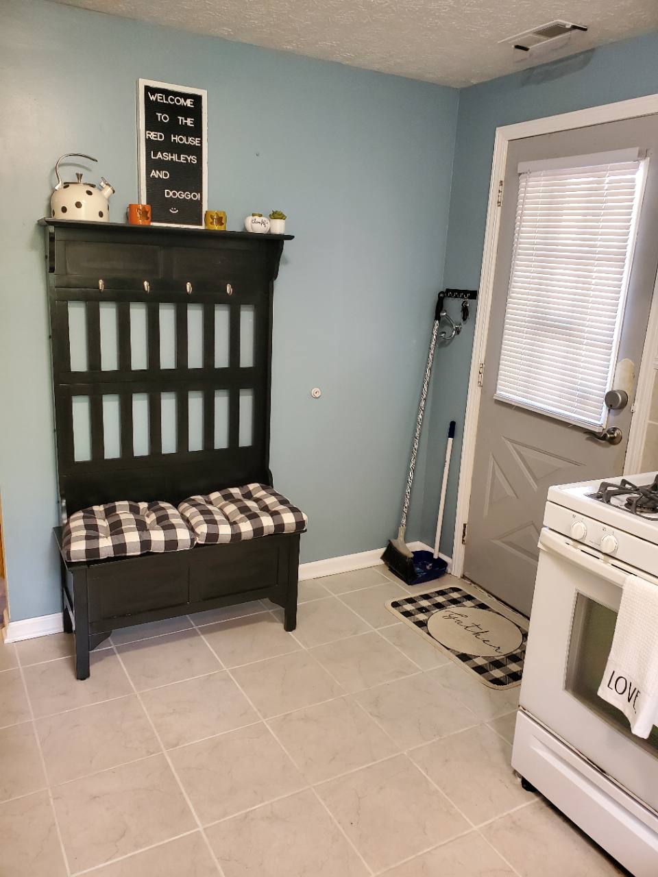 Kitchen entry with black bench, white gas range and a welcome sign using the former Red House name