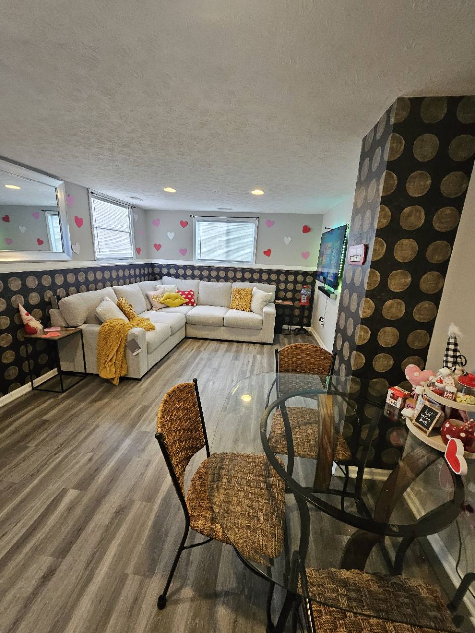 Living and dining area with gray sectional sofa, glass dining table and seasonal heart decorations